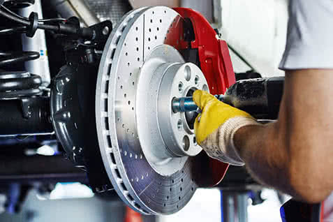 Cropped thumbnail of automotive mechanic replacing brake rotor